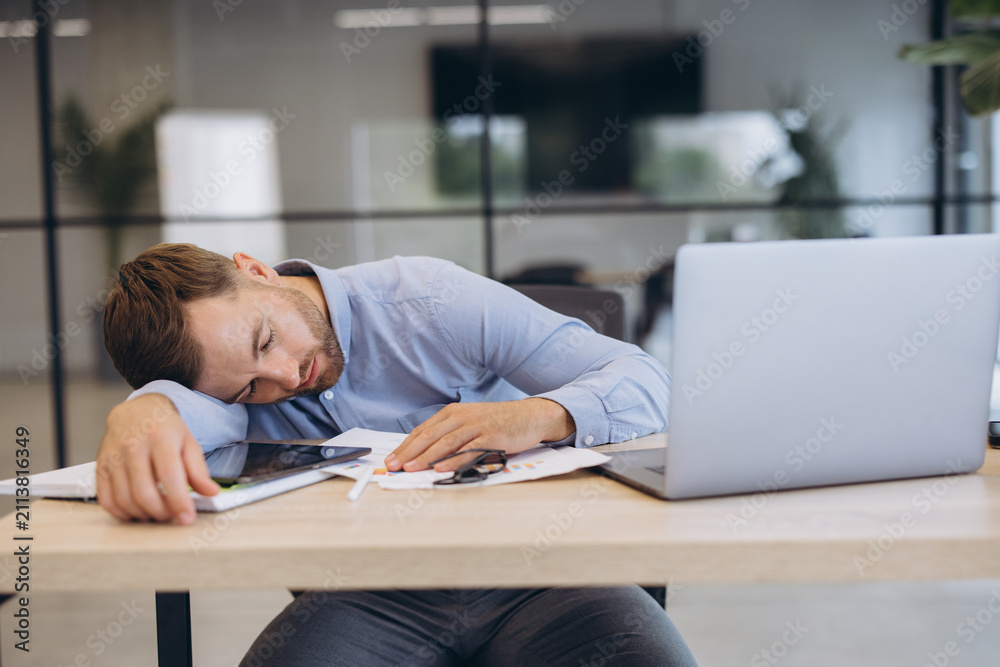 Obraz premium Tired businessman napping at office desk, exhausted male worker sleeping from burnout, overwork, or stress
