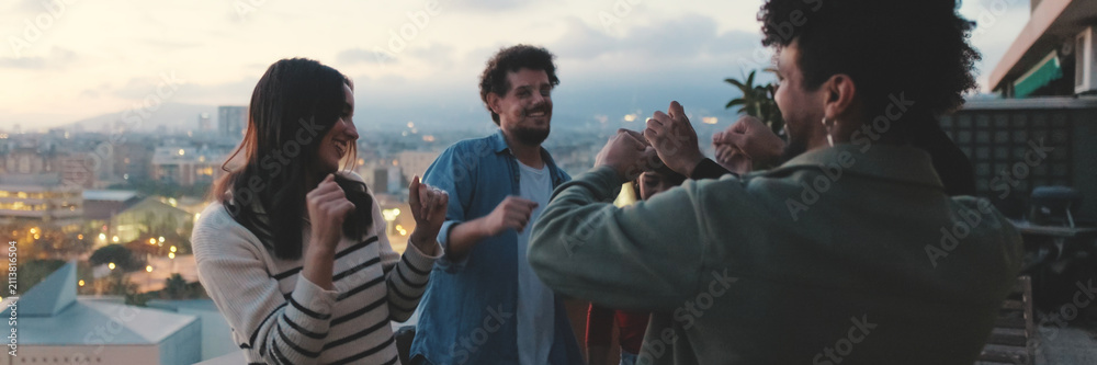 Fototapeta premium Guys and girls at party, dancing and having fun on the terrace, friendly party holiday at sunset. Panoramic