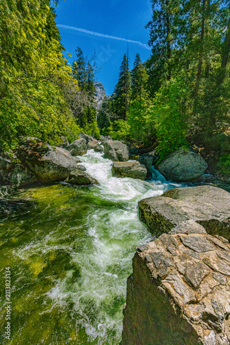 Cuadro en lienzo Clear emerald green water churning over granite rocks and boulders along the Merced River enclosed by vibrant green trees in Yosemite Valley