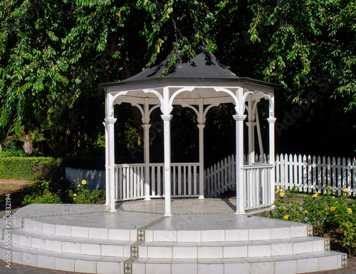 Canvastavla White wooden gazebo surrounded by lush foliage in a sunny park