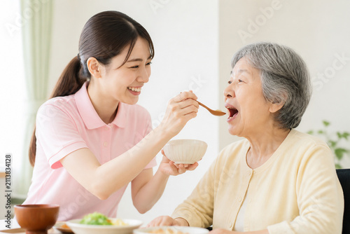 高齢女性の食事介助をする笑顔の介護士 Generative AI
