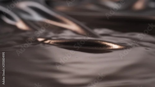 Luxurious dark metallic liquid silk flows in slow motion, rippling with elegant high-contrast lighting that creates soft, sophisticated highlights across a satisfyingly smooth and tactile surface.