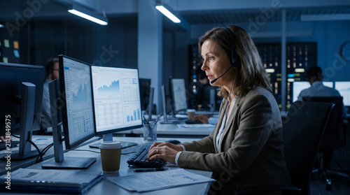 This beautiful and highly detailed stock photograph captures a dedicated night shift call center agent wearing a headset while working under moody blue lights right here.