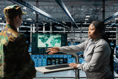 Fotografie A team of military experts reviews geopolitical data on a digital map while a female army information specialist and commander analyze worldwide threat indicators in a server farm