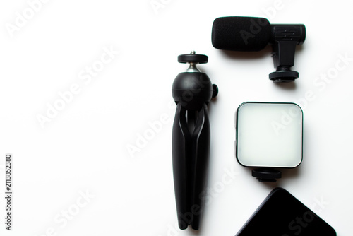 Equipment for content creators and vloggers, including a microphone, tripod, led light, and smartphone, representing online communication and digital media production