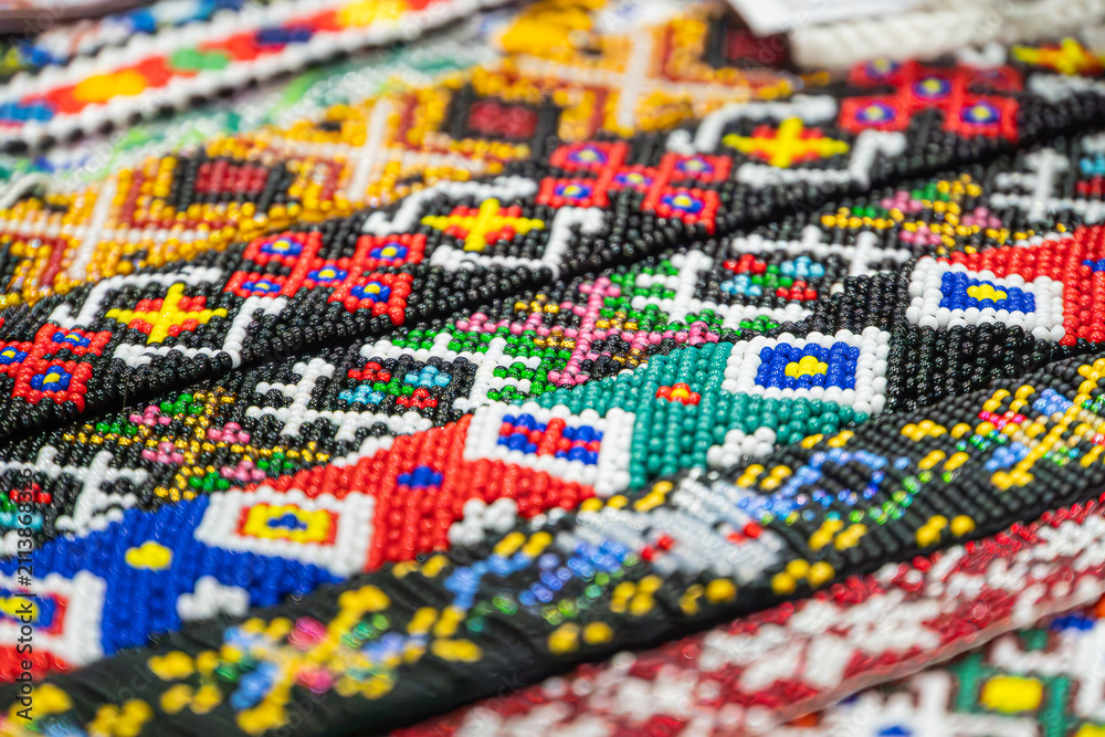 Obraz premium Vibrant beadwork pattern in bright primary and secondary colors, showcasing intricate artisanal design, detailed craftsmanship, colorful repetitive symmetrical arrangement