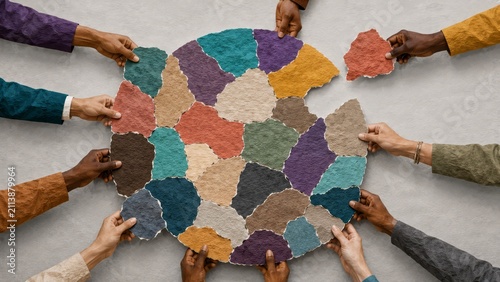 Diverse hands collaboratively assembling colorful torn-paper puzzle pieces into a circular map-like composition symbolizing teamwork, unity, inclusion and global cooperation