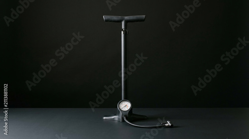 Black bicycle pump with pressure gauge, showcasing a practical tool for inflating tires, symbolizing maintenance, readiness, and activity.