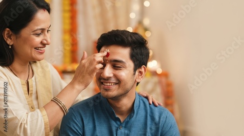 Indian woman applying tilak on forehead of young man during traditional festival celebration ceremony at home representing family bonding and culture