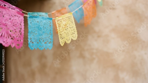 Colorful Mexican papel picado banners hanging outdoors for fiesta celebration, festive decoration concept for traditional holidays and cultural events