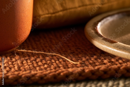 Macro view of wool throw, ceramic mug and mustard cushion by candlelight