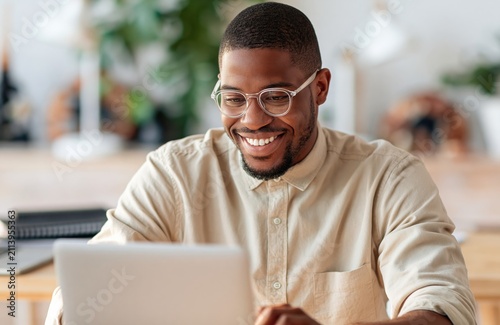 Man african american working on laptop in a bright modern business office space