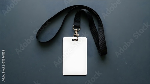 Blank white plastic ID badge with black lanyard on a dark surface