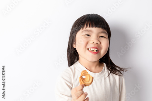 A little girl eating a snack against a white background