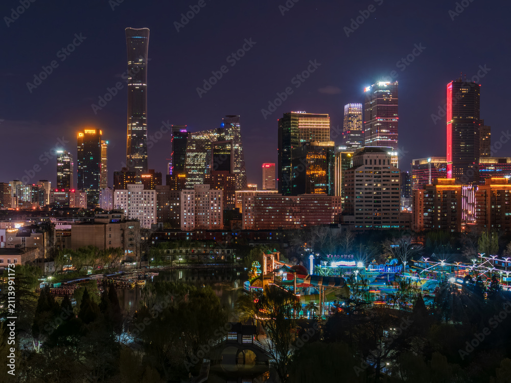 Fototapeta premium Night view of Beijing's CBD skyscrapers and the interplay of light and shadow on park greenery.