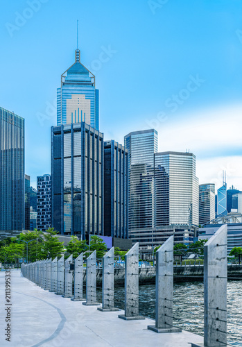 Modern office towers along the waterfront in Hong Kong's Wanchai business district, viewed from a scenic harbourfront promenade.