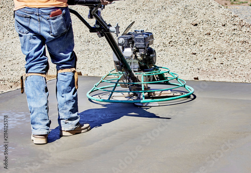 Concrete Worker using a Power Trowel to smooth out Wet Concrete
