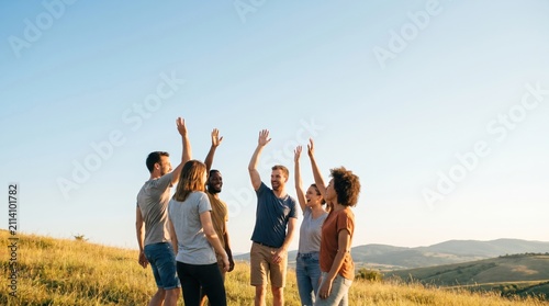 Diverse group of young adult friends raising hands together in victory and celebration outdoors on a sunny hill
