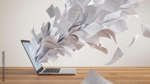 Laptop computer with many documents flying out of the screen