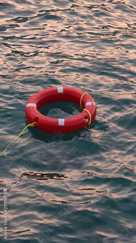 Orange lifebuoy floating on sea water at sunset safety and rescue concept	