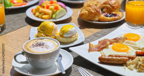 Photography Gourmet breakfast spread sitting on wooden table with eggs benedict fried eggs bacon coffee and fresh fruit, bright morning light, luxury hotel dining hospitality travel lifestyle