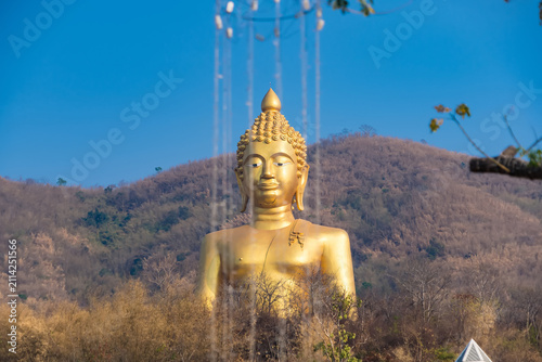 Golden Buddha Statue Amidst Nature: A majestic golden Buddha statue stands tall against a backdrop of rolling hills, with water features creating a serene and spiritual ambiance.