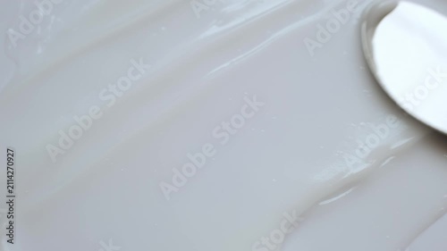 Smooth white cosmetic cream or lotion smeared with metal spatula showing its rich texture