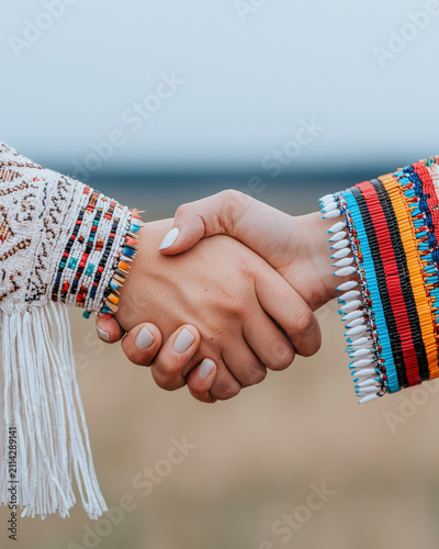 Handshake hand ceremonial clothing sleeve textile fringe bead close view of people greeting with decorative traditional garment outdoors