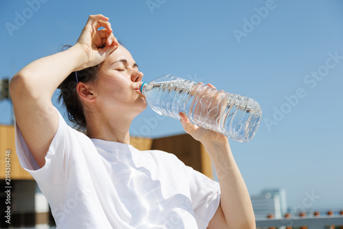 Fotografie Woman drinking water during an extreme summer heatwave outdoors