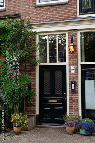 Brick residential entrance with black door and potted plants