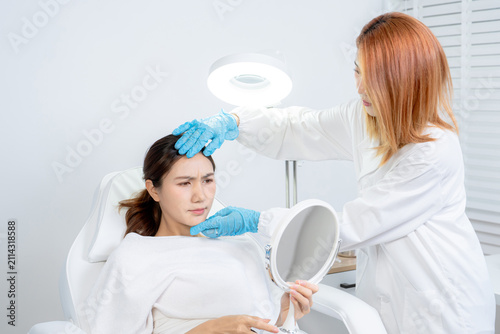 Asian woman consulting with a doctor at a modern aesthetic clinic for facial treatment.