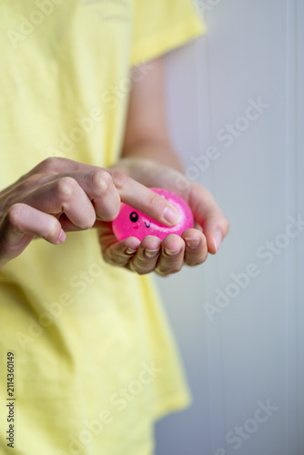 Hands gently press a pink squishy stress toy during sensory play in close-up. Concept of tactile stimulation, focus, stress relief and emotional regulation.