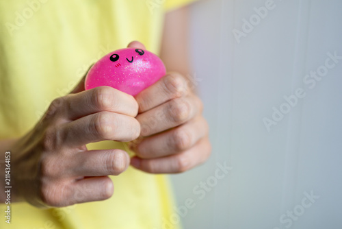 Hands compress a soft pink squishy toy during tactile sensory activity. Concept of stress relief, emotional regulation, calming routine and focus.