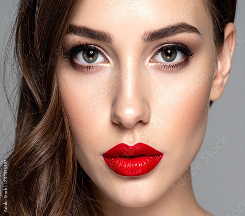 Close-up glamour portrait of a young woman with intense gaze and striking bold red lips.