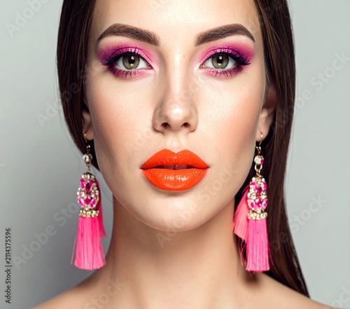 Close-up beauty portrait of a woman with vibrant colorful eye makeup and bright orange lips.
