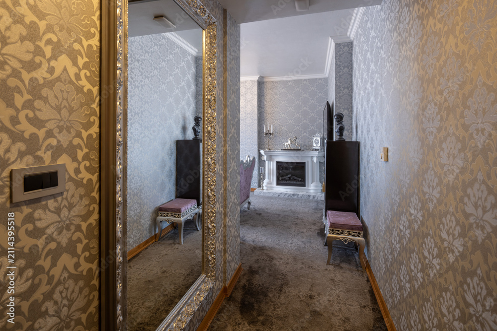 Obraz premium Elegant hotel corridor with large silver mirror and fireplace decor