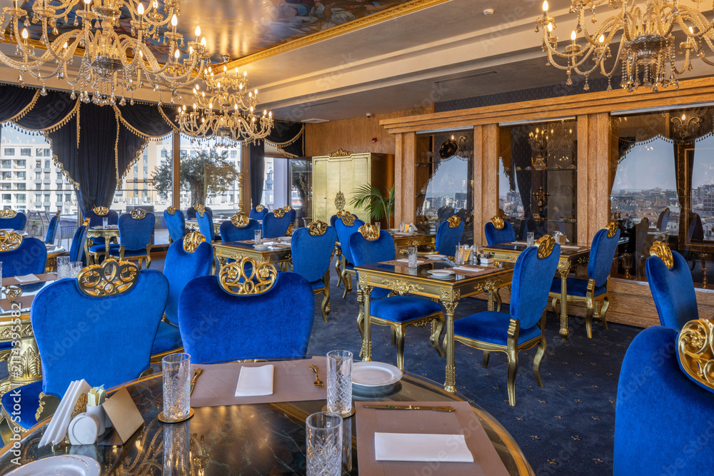 Fototapeta premium Luxury restaurant dining hall with blue velvet chairs and chandeliers