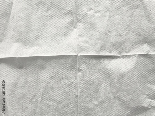 Close-up of white paper napkin texture background with embossed pattern and fold lines.