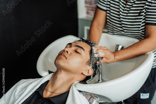 Konstfotografi Hair stylist rinsing and washing young man's hair before professional haircut in