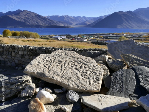 Mani stone with tibetan prayer in front of pangong tso lake in ladakh. Scenic travel background