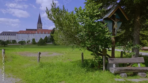 Wegkreuz und Bank dahinter die Erzabtei Sankt Ottilien, Kloster der Missionsbenediktiner, Eresing, Bayern, Deuschland