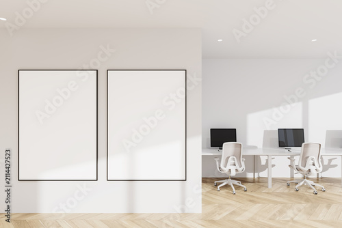 Minimal interior with two large blank poster mockup frames on a clean wall beside bright modern workspace in light office layout design template canvas wall picture light.. 3D Rendering