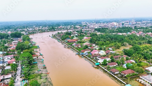 Cuadro en lienzo Aerial view of a brown river flowing through a residential area in a tropical village