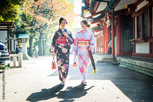Картината върху платно Two beautiful japanese women wearing traditional yukata clothing and going to th