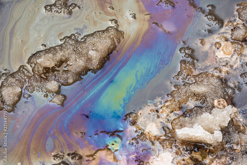 Obraz premium Iridescent oil slick on a road with melting snow, showcasing environmental pollution during springtime melt