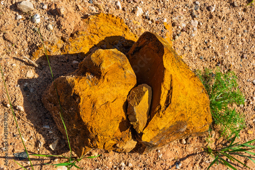 Obraz na płótnie Cracked limonite boulder showcasing vibrant yellow ochre pigment deposits, resti