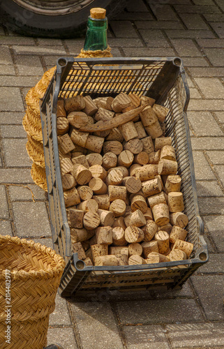 фотографія Natural wine corks fill a plastic crate beside wicker baskets and a glass carboy