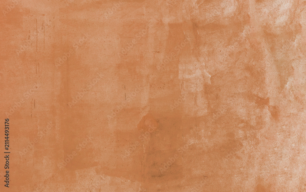 Fototapeta premium Warm terra cotta orange painted wall background showcasing a softly mottled stucco texture and subtle surface scratches, ideal for vintage-inspired graphic design and overlay projects.