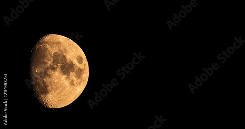 Detailed golden gibbous moon moving across black sky night time lapse