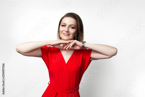Young happy girl in red dress with hands under chin. Isolated on white background.